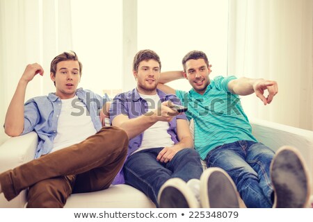 Foto stock: Res · amigos · en · la · sala · de · estar · viendo · la · televisión · sonriendo