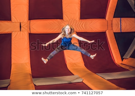 Foto stock: Young Woman Sportsman Jumping On A Trampoline In Fitness Park And Doing Exersice Indoors