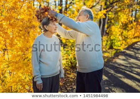 Foto stock: Happy Old Couple Having Fun At Autumn Park Elderly Man Wearing A Wreath Of Autumn Leaves To His Eld
