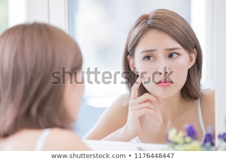 Foto stock: Upset Young Asian Woman With Her Hands On Cheek