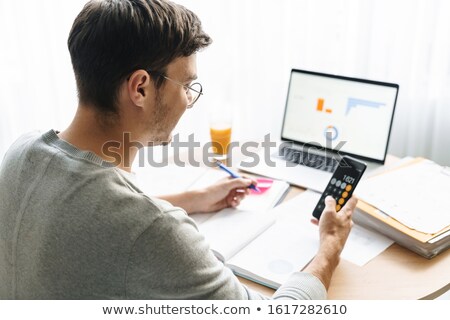 Zdjęcia stock: Image Of Young Man Doing Calculations While Working On Laptop At