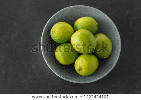 Stock photo: Close Up Of Whole Limes In Bowl On Slate Table Top