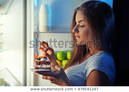 Stock fotó: Young Woman Eating A Piece Of Cake At Night