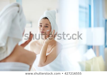 Stok fotoğraf: Beautiful Young Woman Applying Foundation On Her Face With A Make Up Brush Isolated On Gray Backgrou