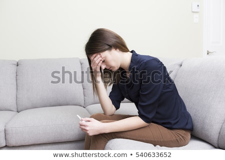 ストックフォト: Girl Sitting On A Couch At Home While Reading The Results Of Her Recent Pregnancy Test