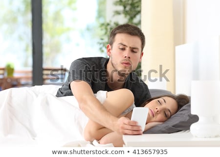 Foto stock: Man Reading In Bed As His Partner Sleeps