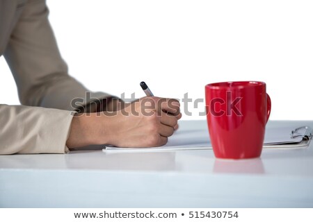 Foto stock: Businesswoman Writing On Clipboard With Coffee Mug On Desk