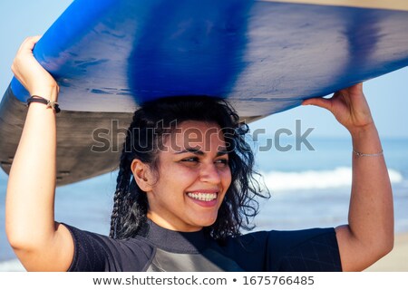 Foto d'archivio: Portrait Of Cheerful Woman Standing With Surfboard On Shore