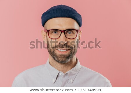 Foto stock: Close Up Portrait Of Smiling Unshaven Male Rejoices Good News Wears Hat And Shirt Looks With Eyes