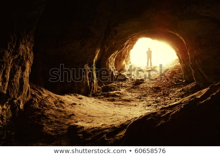 Foto stock: Ombre · de · pie · delante · de · la · entrada · de · una · cueva