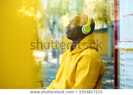 Stok fotoğraf: African Young Man Listening To Music At Bus Stop