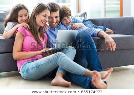 Foto stock: Father With Son Relaxing On The Couch Using Laptop