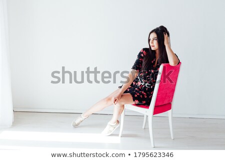 商業照片: Stunning Brunette Sitting And Posing On A Chair In Fashion Dress