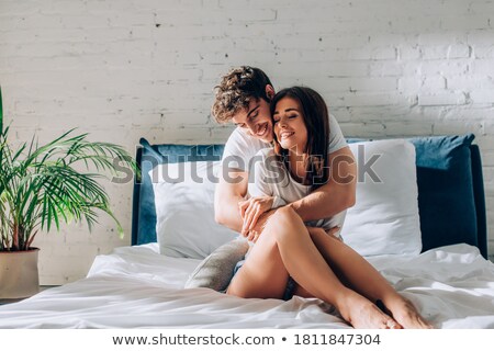 Foto stock: Tender Young Couple Sitting And Embracing In Bed