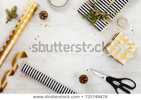 Stok fotoğraf: Gift Box In Gold Wrapping Paper With Ribbon On Wooden Table