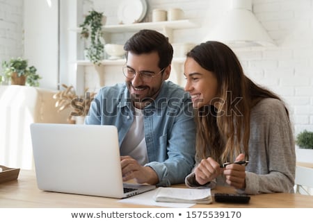 Stock photo: Woman Using Calculator At Kitchen Table