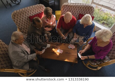 Stockfoto: High Angle View Of Group Of Senior Friends Playing Cards At Nursing Home