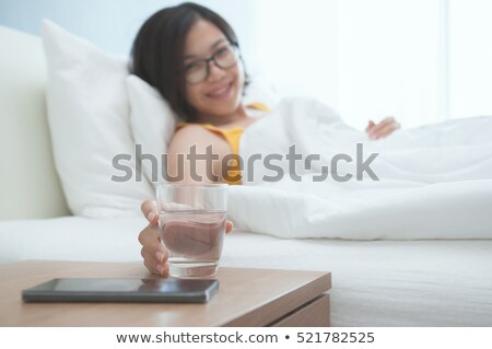 Foto d'archivio: Glass Of Water And Phone In Bed