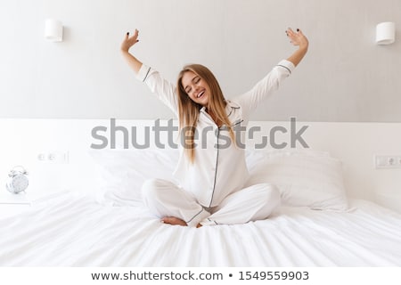Stock photo: Woman Stretching Her Arms While Sitting On Bed