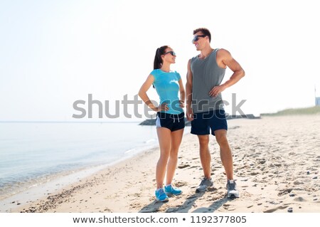 Сток-фото: Happy Couple In Sports Clothes And Shades On Beach