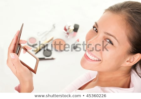 Portrait Of Smiling Young Woman Putting On Make Up Stok fotoğraf © Ariwasabi