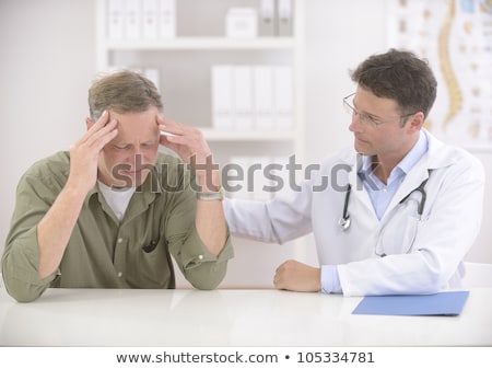 Doctor Comforting Mature Stressed Patient With Headache Imagine de stoc © mangostock