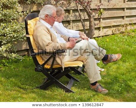 Foto d'archivio: Couple Sitting In Garden Facing Camera