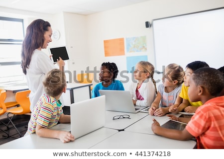 Stok fotoğraf: Child With Technology Tablet And Laptop Computer In Classroom Teacher On The Background