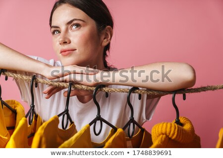 Stock photo: Photo Of Thinking Woman Looking Upward While Leaning On Clothes Rack
