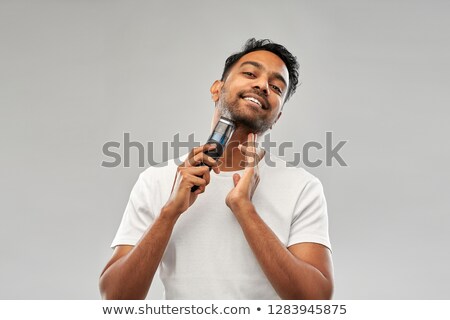 [[stock_photo]]: Smiling Indian Man Shaving Beard With Trimmer