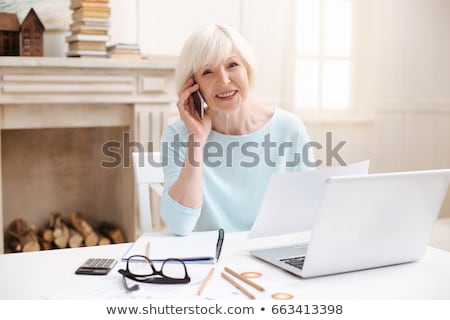 Foto stock: Senior Woman With Laptop Calling On Smartphone