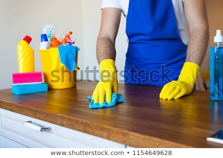 Stock photo: Closeup Of Young Man Wearing Apron Cleaning Kitchen Worktop