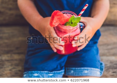 Stockfoto: The Boy Is Holding Healthy Watermelon Smoothie In Mason Jar With Mint And Striped Straws On A Wood B