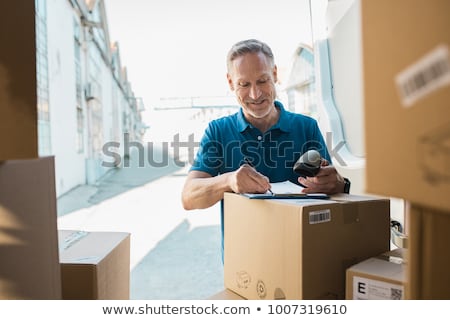 Foto stock: Ntregador · em · pé · com · van · escrevendo · na · prancheta · sorrindo