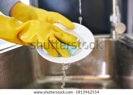 Stok fotoğraf: Woman With Rubber Gloves Washing The Dishes