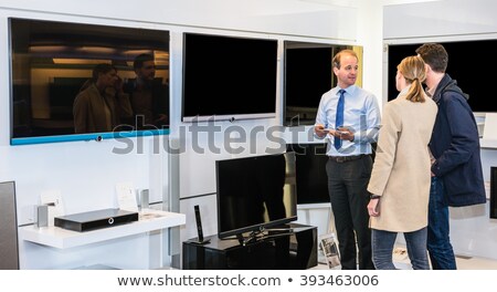 ストックフォト: Assistant Showing Flat Screen Tv To Couple In Hypermarket