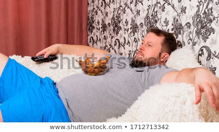 Foto stock: Close Up Of Man With Tv Remote Drinking Beer
