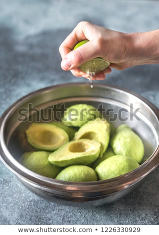 Stok fotoğraf: Hand Squeezing Lime On Halved Avocados