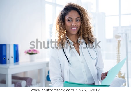 Stock photo: Happy Smiling Doctor Holding Clipboard Standing In Hospital Hallway
