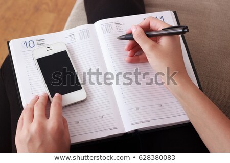 [[stock_photo]]: Woman Writing Contact List From Phone Into Business Agenda