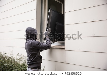 Stockfoto: Robbers Stealing Television Through House Window