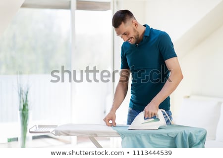 Foto stock: Man Ironing Shirt By Iron At Home