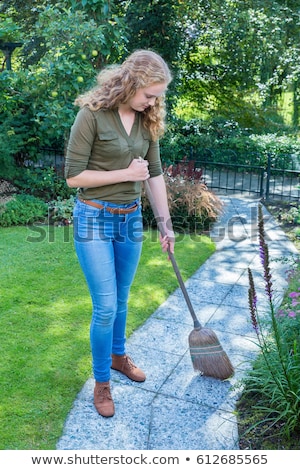 Stock photo: Young Dutch Woman Sweeps Garden Path With Wicker Broom