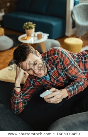 Foto stock: Man Lying On Sofa Using Cell Phone