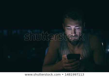 Foto d'archivio: Young Cell Phone Addict Man Awake Late At Night In Bed Using Smartphone