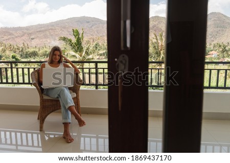 Foto stock: Young Woman Is Working On A Laptop On Her Balcony Overlooking The Skyscrapers Freelancer Remote Wo