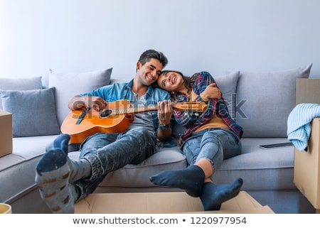 Foto stock: Smiling Beautiful Couple Sitting On A Sofa At Their Apartment An