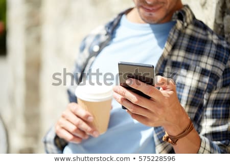 Foto d'archivio: Man Texting Message On Smartphone At Stone Wall