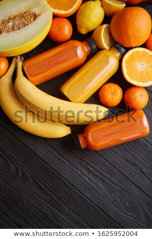 Stock photo: Yellow And Orange Fruits And Botteled Juices Placed On Black Wooden Background