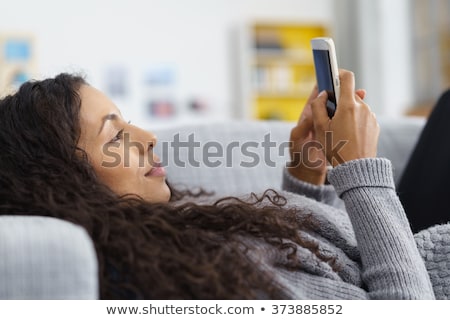 ストックフォト: Woman Lying On Sofa While Writing A Text Message On Her Cell Pho